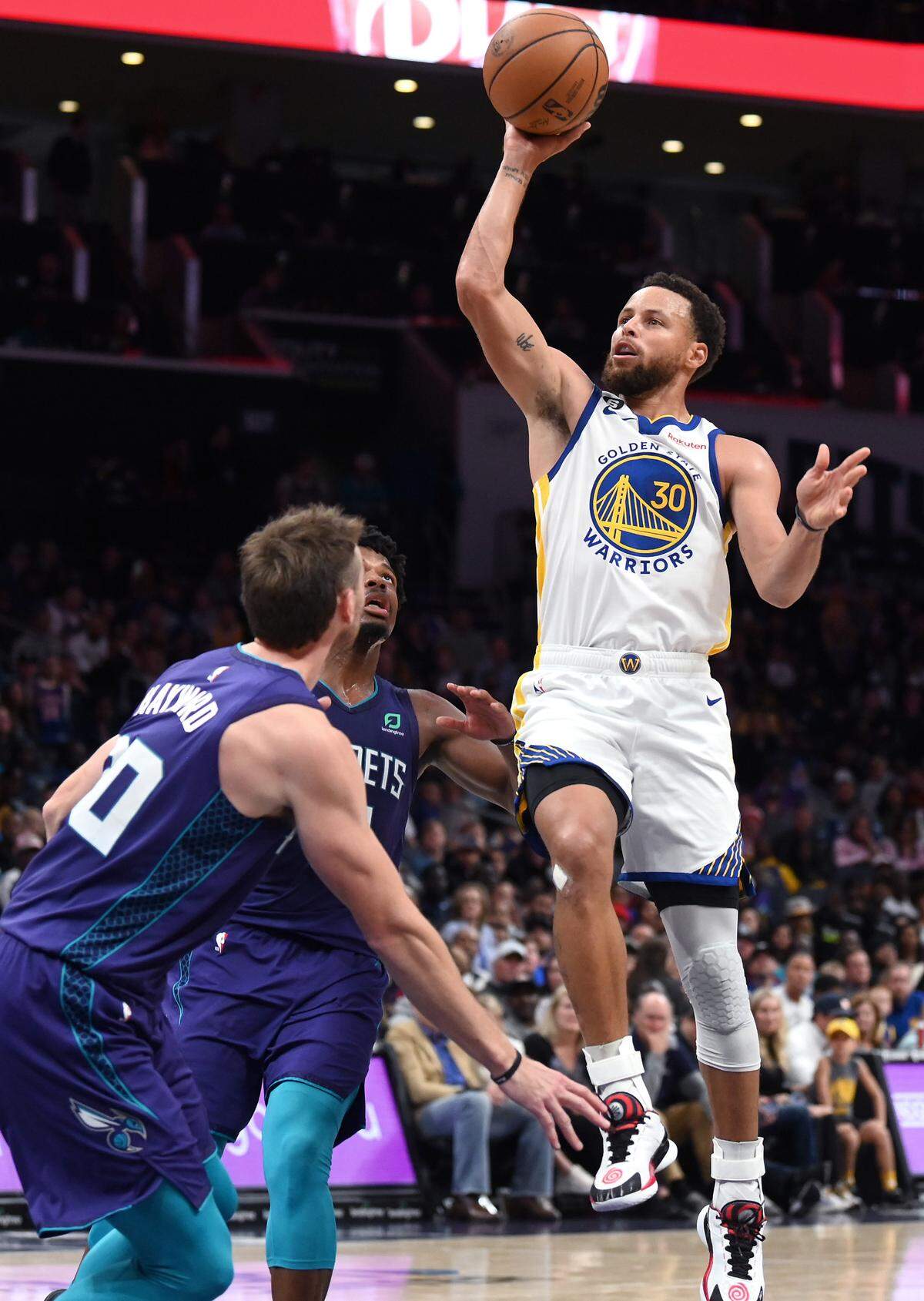 Golden State Warriors guard Stephen Curry, right, releases a running one-handed shot in the lane over Charlotte Hornets guard Dennis Smith Jr.,center and forward Gordon Hayward, left, during second half action at Spectrum Center on Saturday, October 29, 2022. The Hornets defeated the Warriors 120-113.