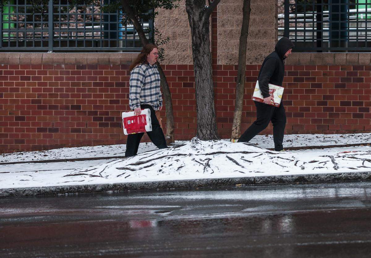 People carry toilet paper up Church Street after a storm front brought rain, snow and sleet to the Charlotte area on Sunday, January 25, 2026.
