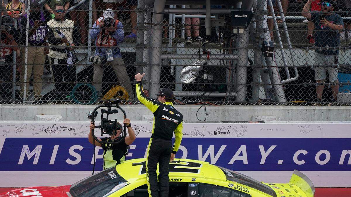 Ryan Blaney stands on his car after winning the NASCAR Cup Series auto race at Michigan International Speedway, Sunday, Aug. 22, 2021, in Brooklyn, Mich. (AP Photo/Carlos Osorio)