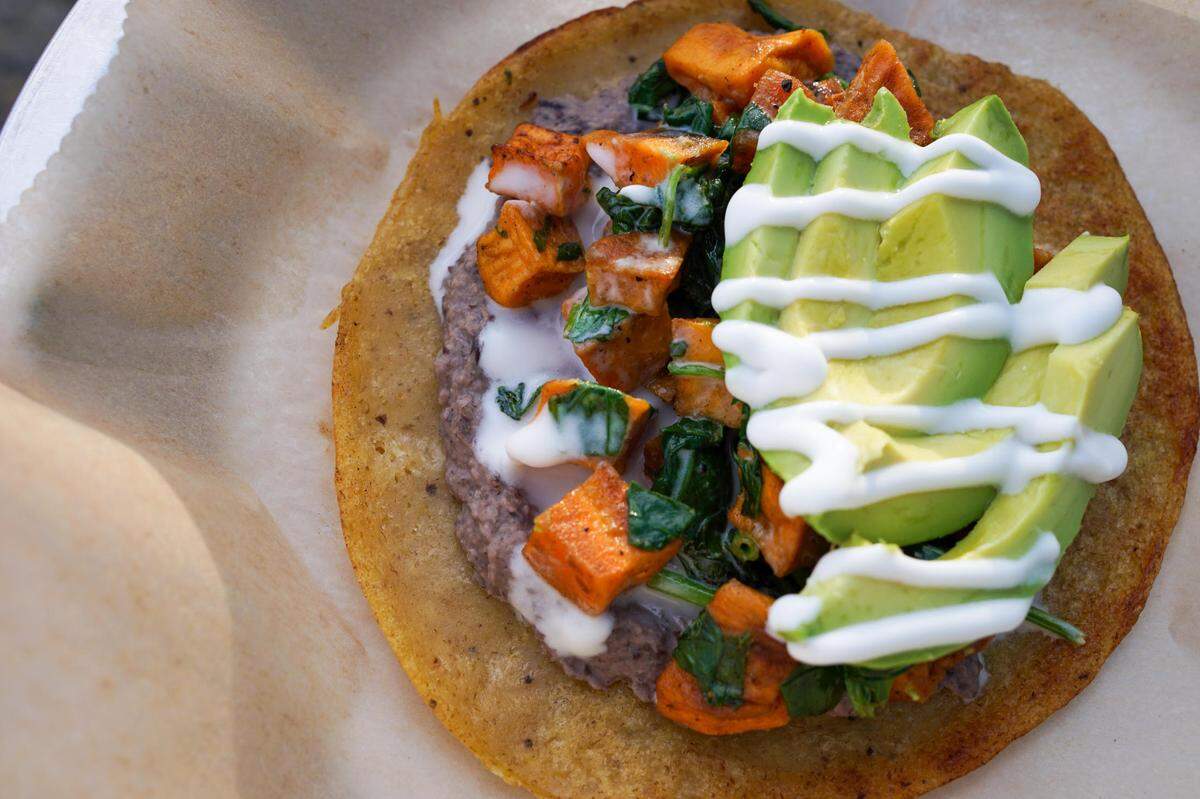 The Support Group taco from Taco Billy made with cumin roasted sweet potatoes, sauteed spinach, Roots black bean hummus, avocado, and coconut crema served on a plantain tortilla.