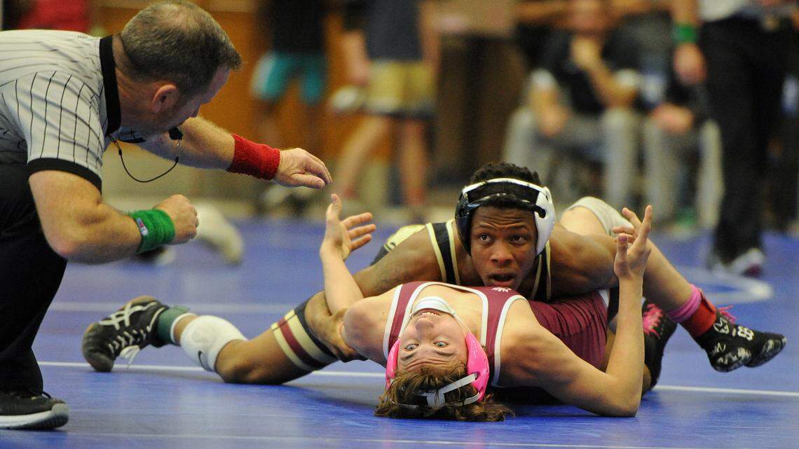 Mallard Creek’s Cameron Stinson Jr., top right, looks over at match official Raye Brothers, left, as he tries to pin South Caldwell’s Mason Yount, bottom right, during their 126-pound semifinal match at the NCHSAA 4A Western Regional individual wrestling championships at Mooresville High School in Mooresville, N.C., on Saturday, Feb. 10 (CREDIT: Bill Kiser/Special to the Observer)