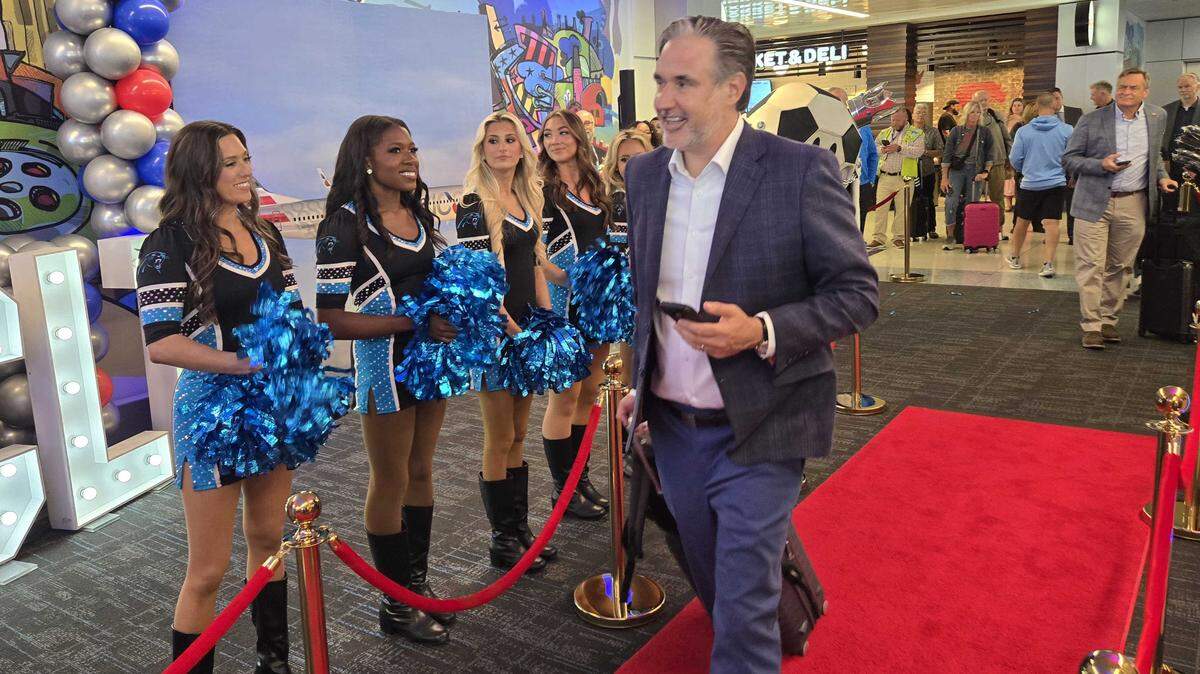 An American Airlines passenger is greeted by company leaders and the Carolina Panthers TopCat Cheerleaders during a centennial celebration on Wednesday.