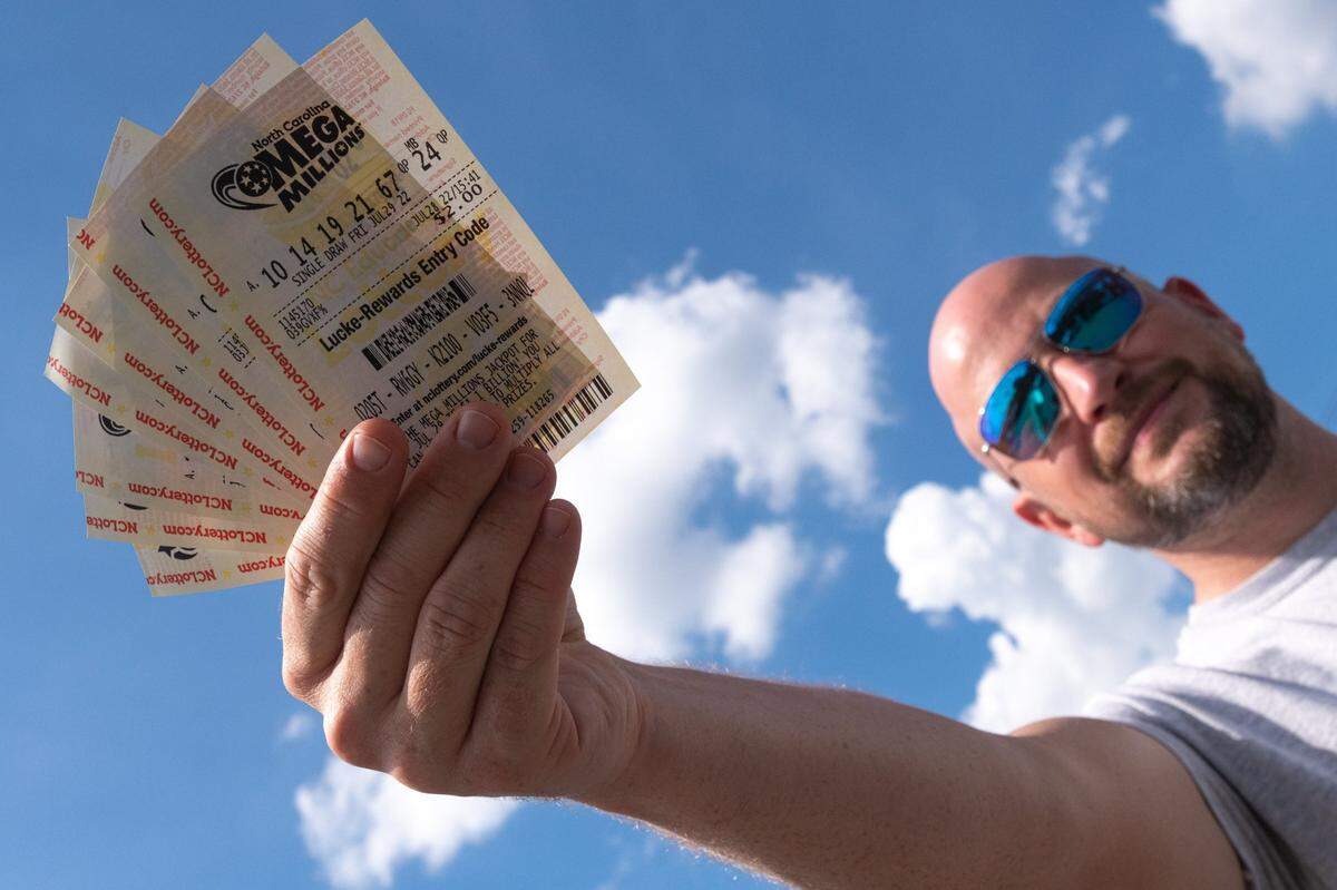 Alston Gore, 38, shows a handful of Mega Millions lottery tickets he purchased from a gas station on Freedom Drive in Charlotte on Thursday, July 28, 2022. “Every time I stop for gas, I grab a lottery ticket,” Gore said. Friday’s jackpot stands at $1.28 billion, with a $747.2 million cash option.