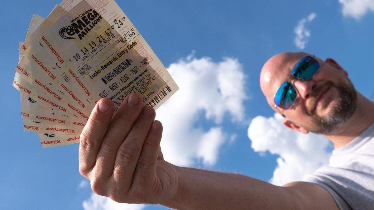 Alston Gore, 38, shows a handful of Mega Millions lottery tickets he purchased from a gas station on Freedom Drive in Charlotte on Thursday, July 28, 2022. “Every time I stop for gas, I grab a lottery ticket,” Gore said. Friday’s jackpot stands at $1.28 billion, with a $747.2 million cash option.
