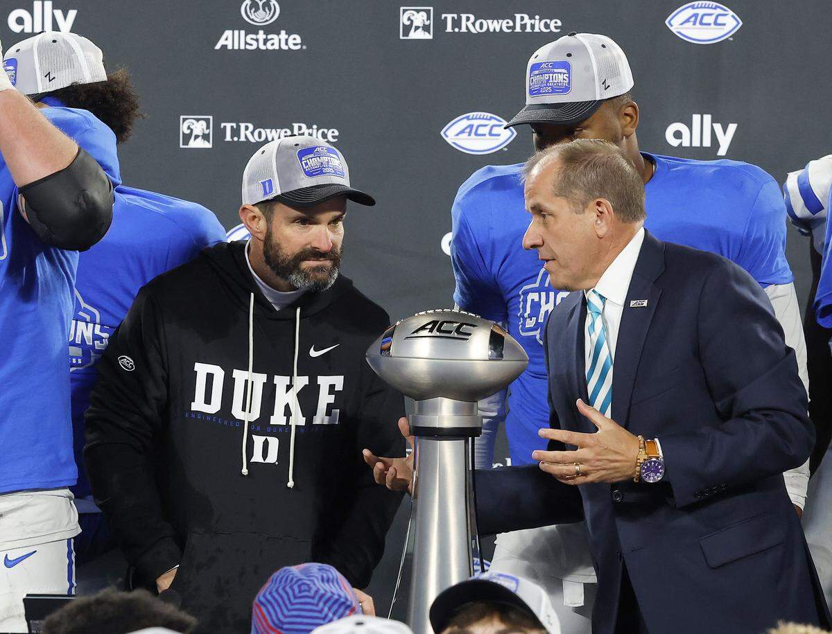Duke head coach Manny Diaz talks with ACC Commissioner Jim Phillips prior to the trophy presentation after the Blue Devils’ 27-20 overtime win over Virginia in the ACC Football Championship in 2025.