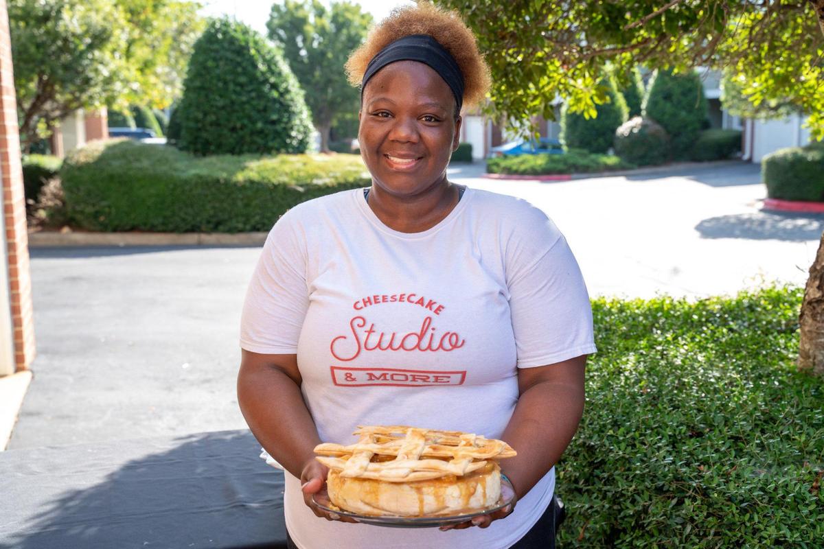Deneka Sampson is the owner of The Cheesecake Studio. She is holding an Apple Pie Cheesecake.