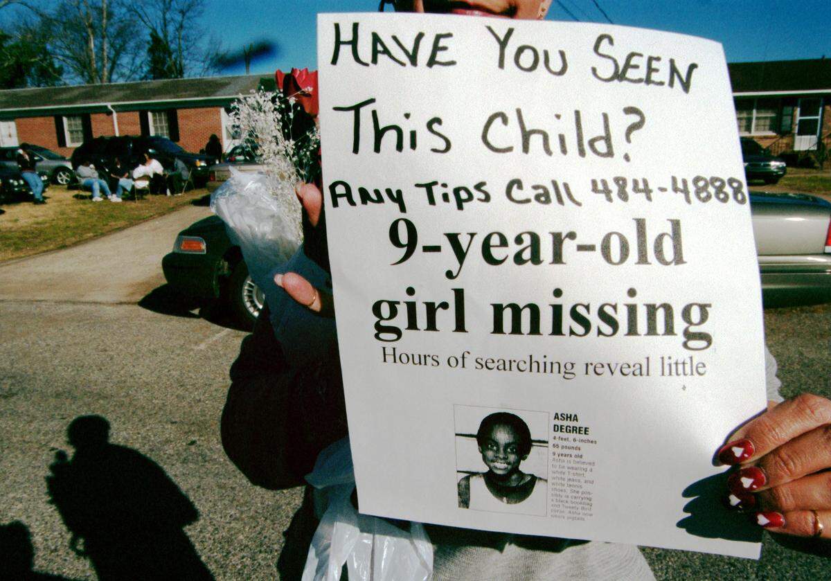 Friends and neighbors distribute fliers hoping to help find nine-year-old Asha Degree on Feb. 15, 2000. Sandy Shaffer (holding the flier) whose sons played baseball with Asha, helped pass out the fliers.