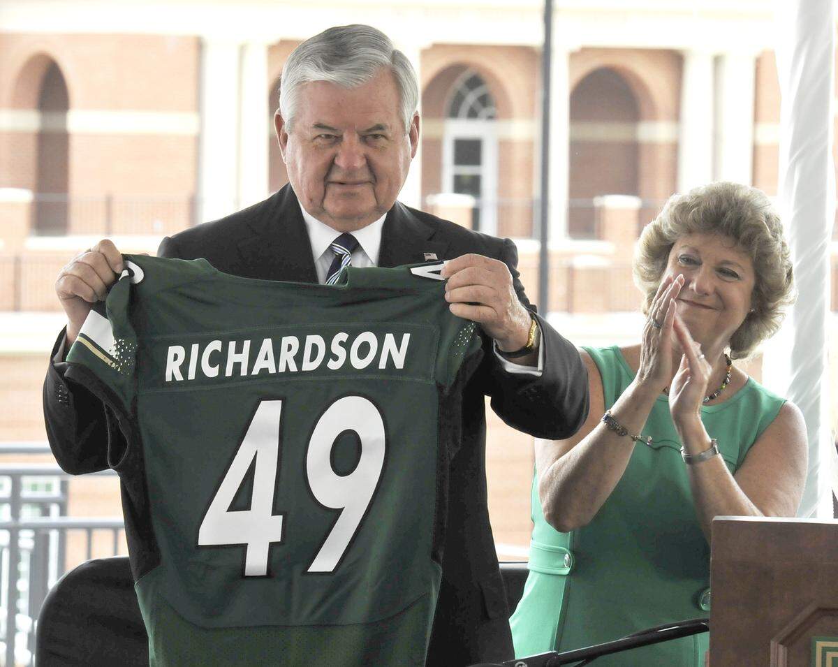 Former Panthers owner Jerry Richardson holds up an honorary football jersey with his name on it after former UNC Charlotte Director of Athletics Judy Rose (back right) announced in 2013 that the 49ers’ football stadium would bear his name.