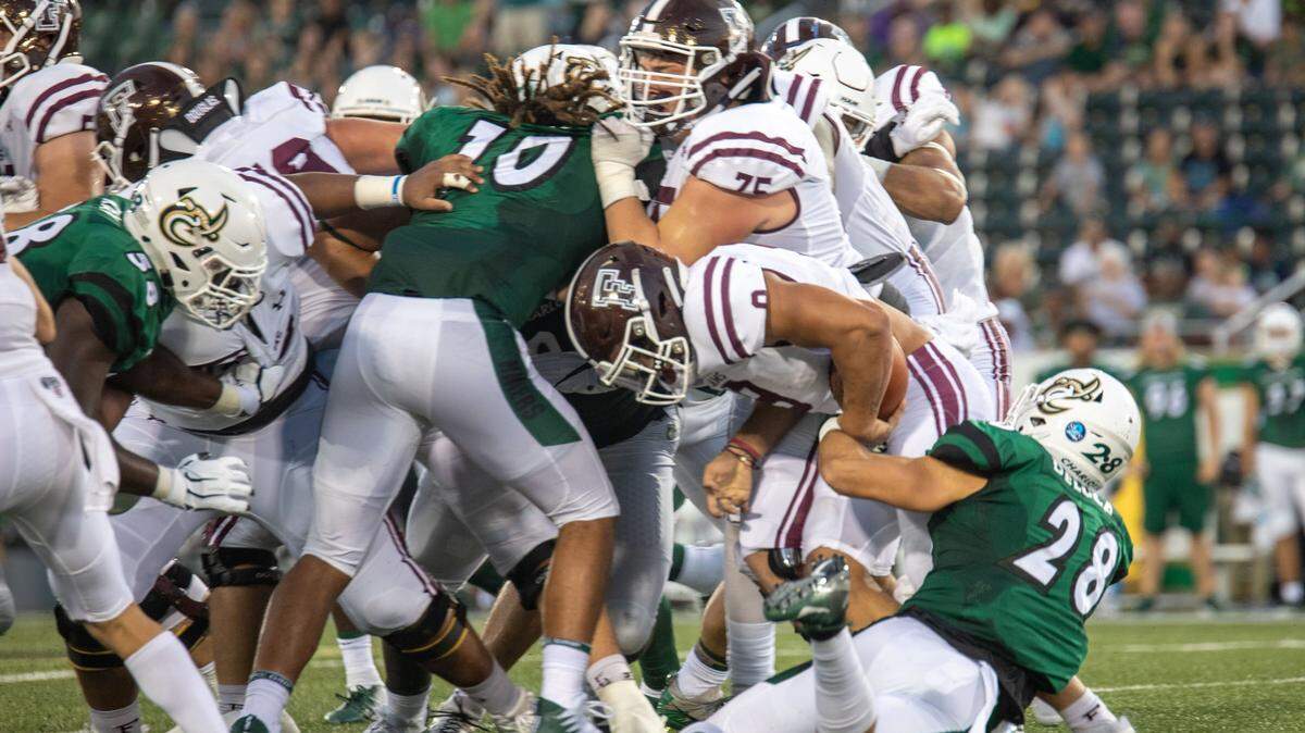 Charlotte’s Ben Deluca (28) brings down Fordham’s Zach Davis (9) in a 2018 game as Tyriq Harris (10) fends off blockers.
