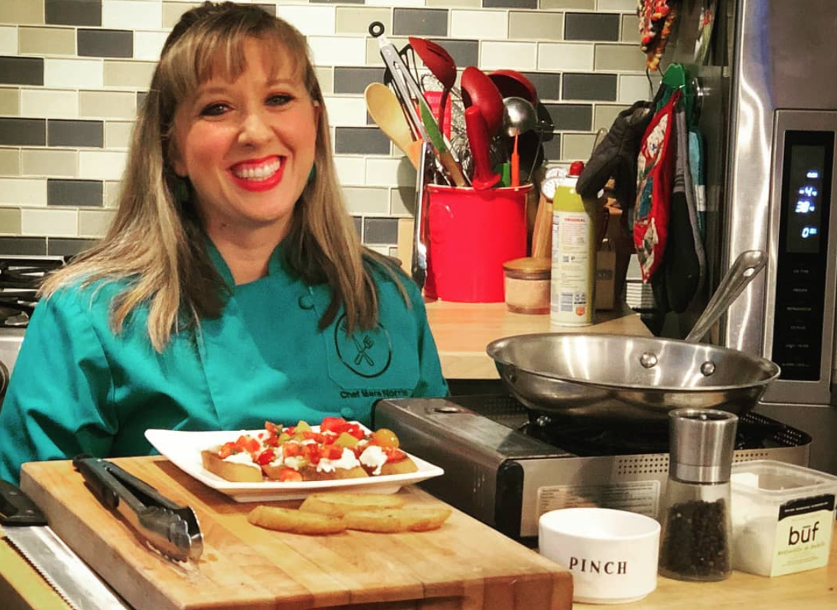 Chef Mara Norris at The Foodie School with a plate of bruschetta.
