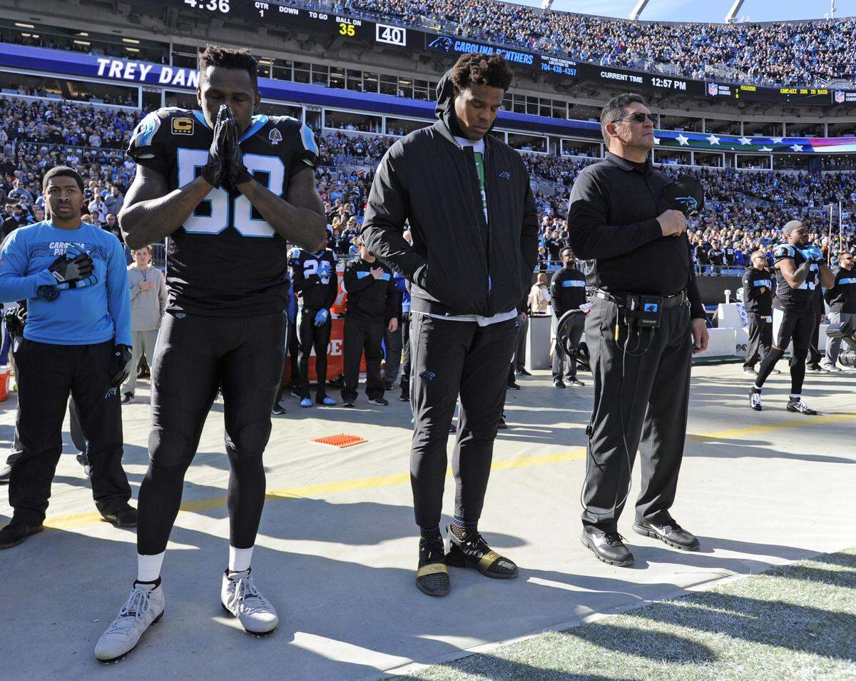 Carolina Panthers head coach Ron Rivera, right, Cam Newton, center, and Thomas Davis, left, sand during the national anthem before an NFL football game against the Atlanta Falcons in Charlotte, N.C., Sunday, Dec. 23, 2018. (AP Photo/Mike McCarn)