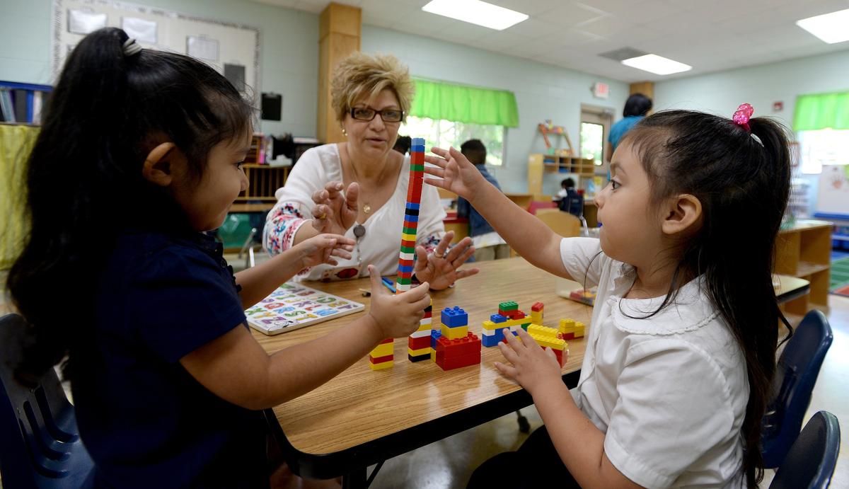 Smart Kids teacher Diana Flores watches Neilyn Guerrero Alcaraz (left) and Sarai Hernandez build with Legos in a state-sponsored public pre-K class. The Smart Kids chain and other private centers will host more children in a Mecklenburg pre-K program that begins Sept. 24.