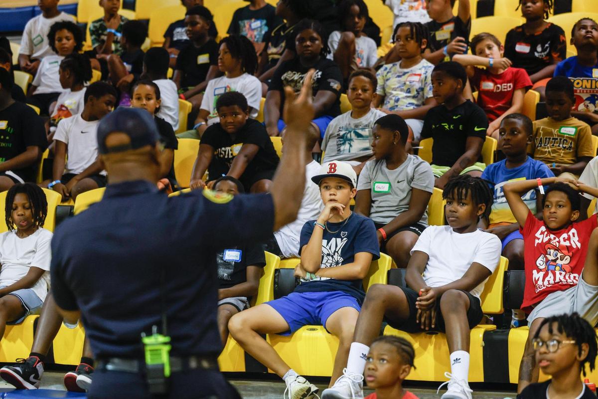 The junior varsity group of boys, ages 8-10 years old, listen as Capt. Brian Cunningham talks about the importance of school during Impact Camp at Johnson C. Smith University in Charlotte on Monday, July 21, 2025. Impact Camp offers 300 spots for a week-long free camp based in teaching young boys the importance of education, entrepreneurship, enlistment, employment and that there are many different positive paths in their lives.