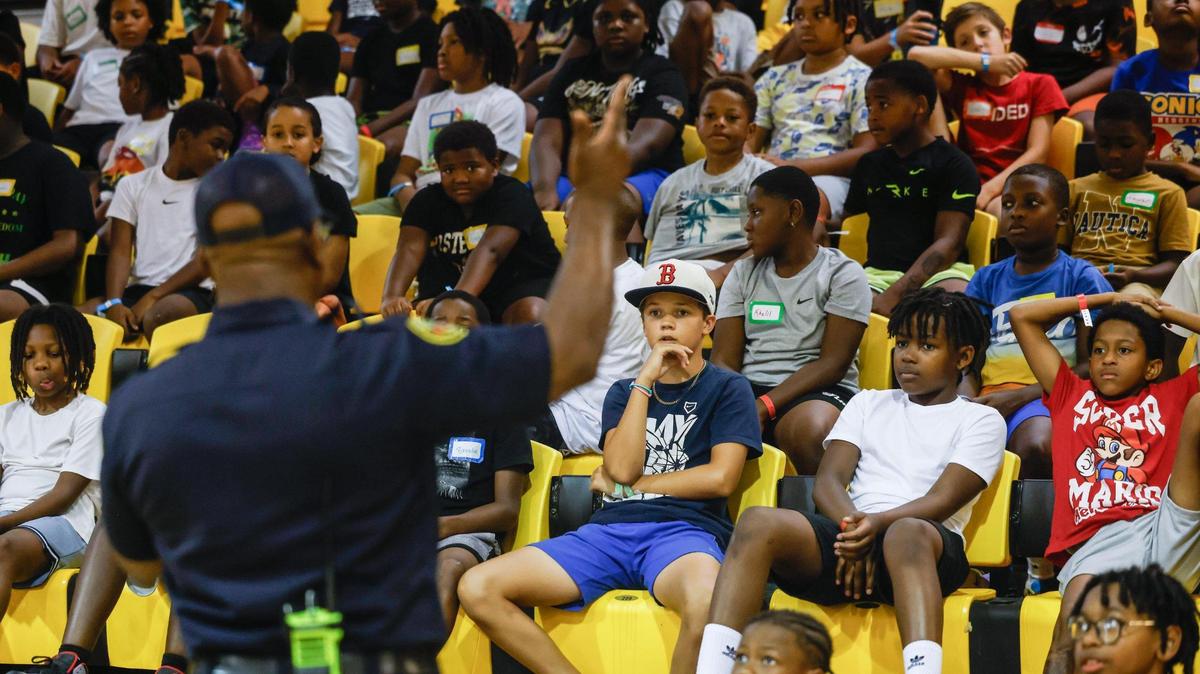 The junior varsity group of boys, ages 8-10 years old, listen as Capt. Brian Cunningham talks about the importance of school during Impact Camp at Johnson C. Smith University in Charlotte on Monday, July 21, 2025. Impact Camp offers 300 spots for a week-long free camp based in teaching young boys the importance of education, entrepreneurship, enlistment, employment and that there are many different positive paths in their lives.