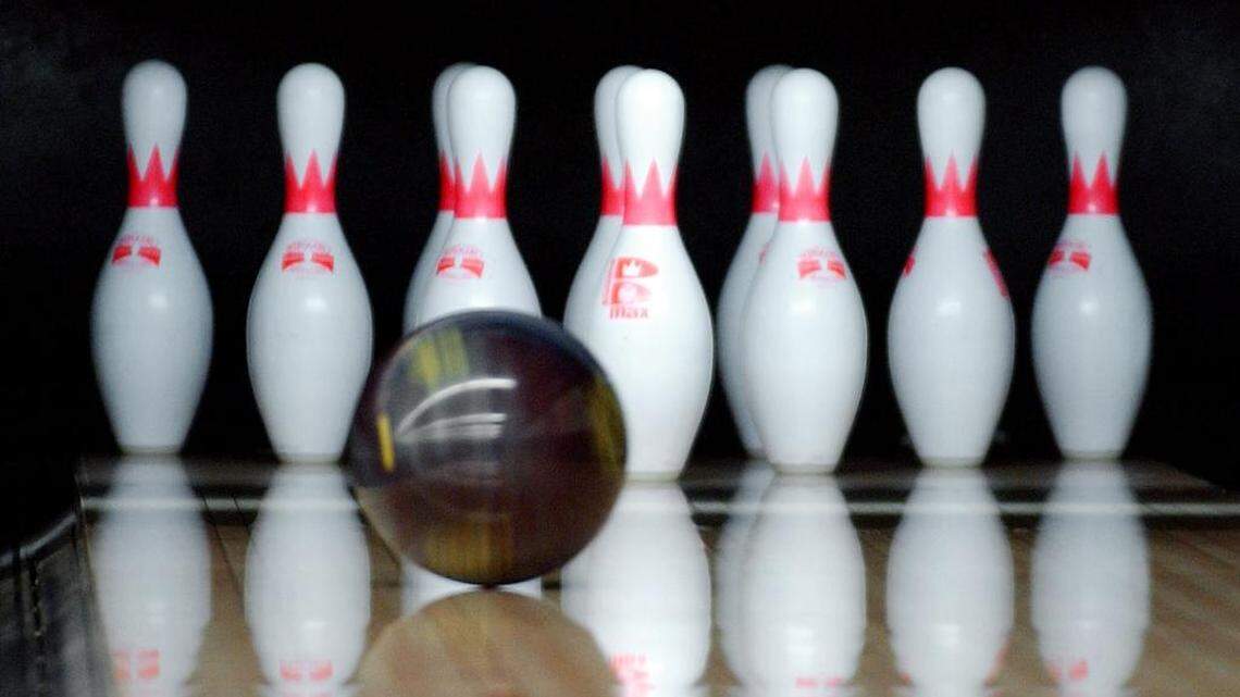 A bowling ball rolling toward pins in a bowling alley.