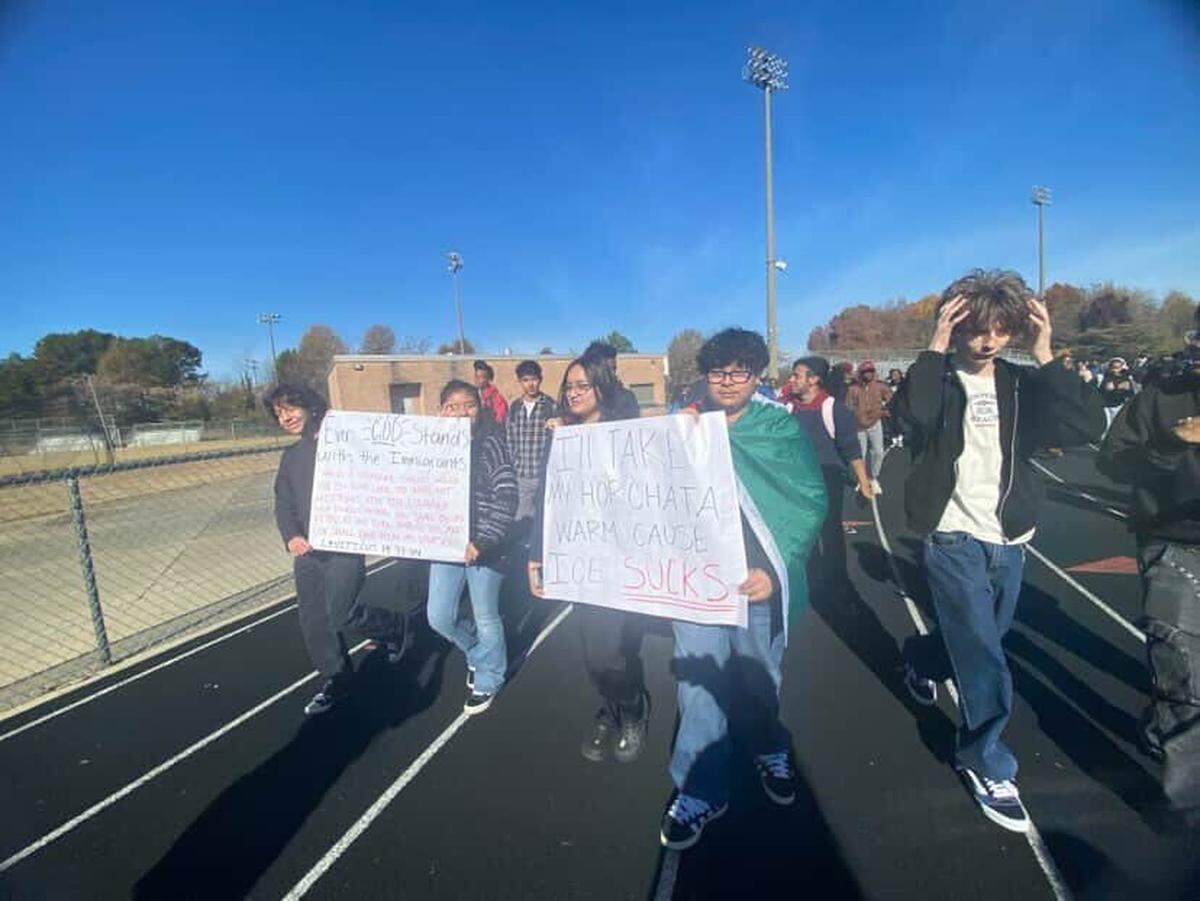 Students carry signs and walk around the track at Phillip O. Berry Academy of Technology in west Charlotte to protest ICE and Border Patrol arrests.