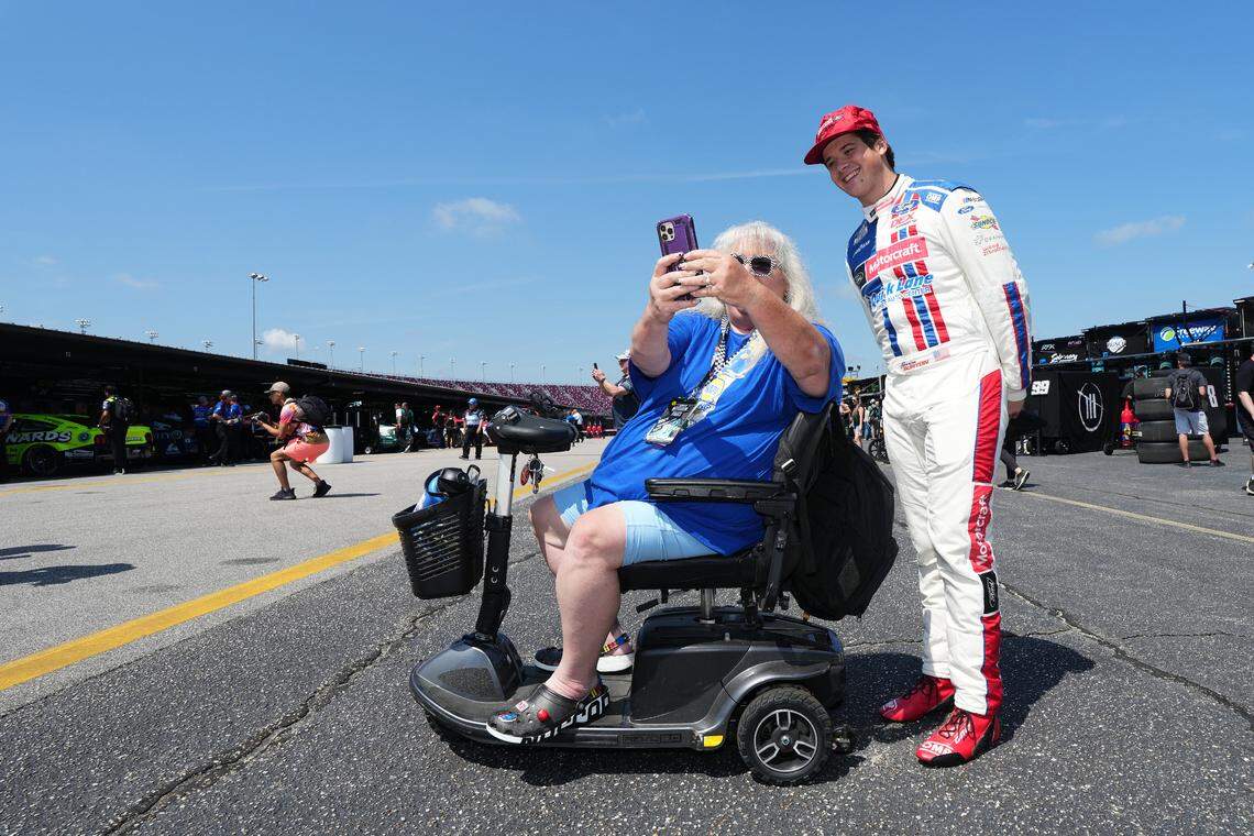 Aug 31, 2024; Darlington, South Carolina, USA; NASCAR Cup Series driver Harrison Burton (R) takes a selfie with a fan prior to practice for the Cook Out Southern 500 at Darlington Raceway