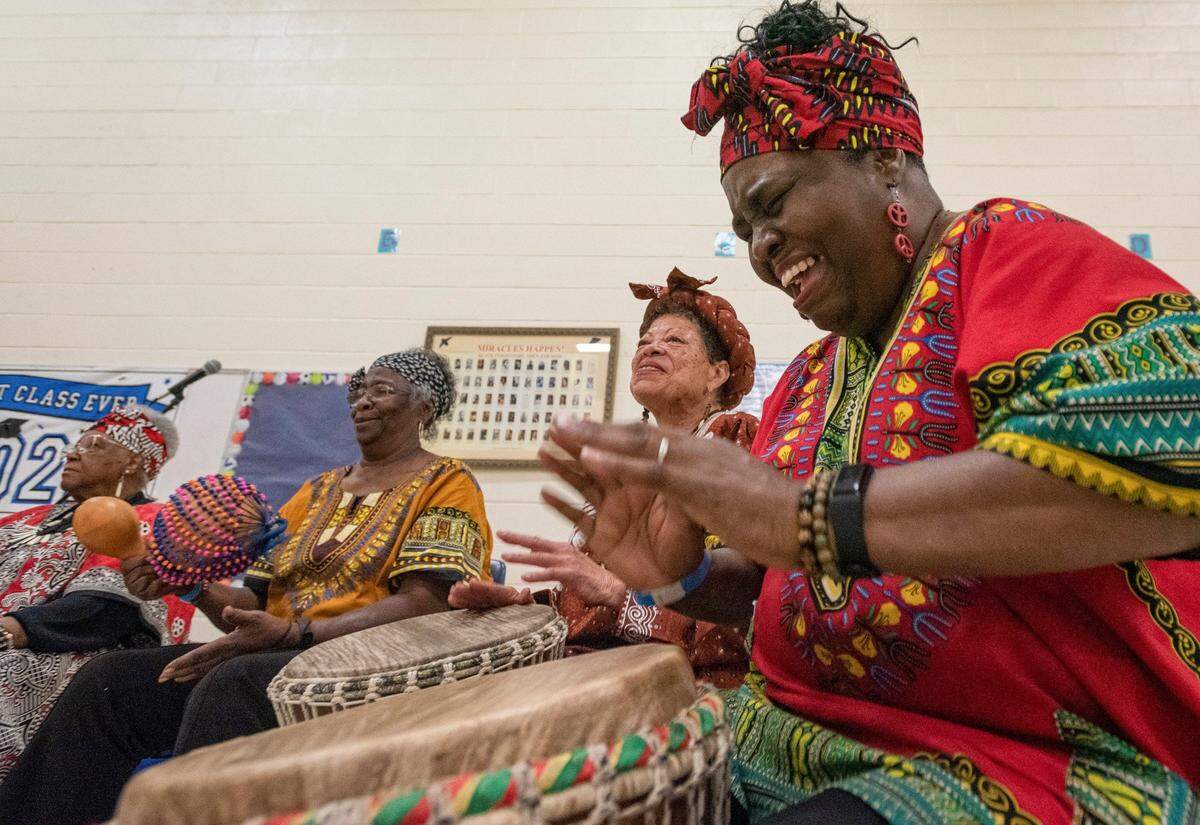 Barbarette Talley, right, of the Queen City Senior African Drummers, plays the djembe alongside several of her groupmates for a crowd of young children during the Juneteenth Festival of the Carolinas culture day camp at Elizabeth Traditional Elementary School in Charlotte, June 16, 2022,