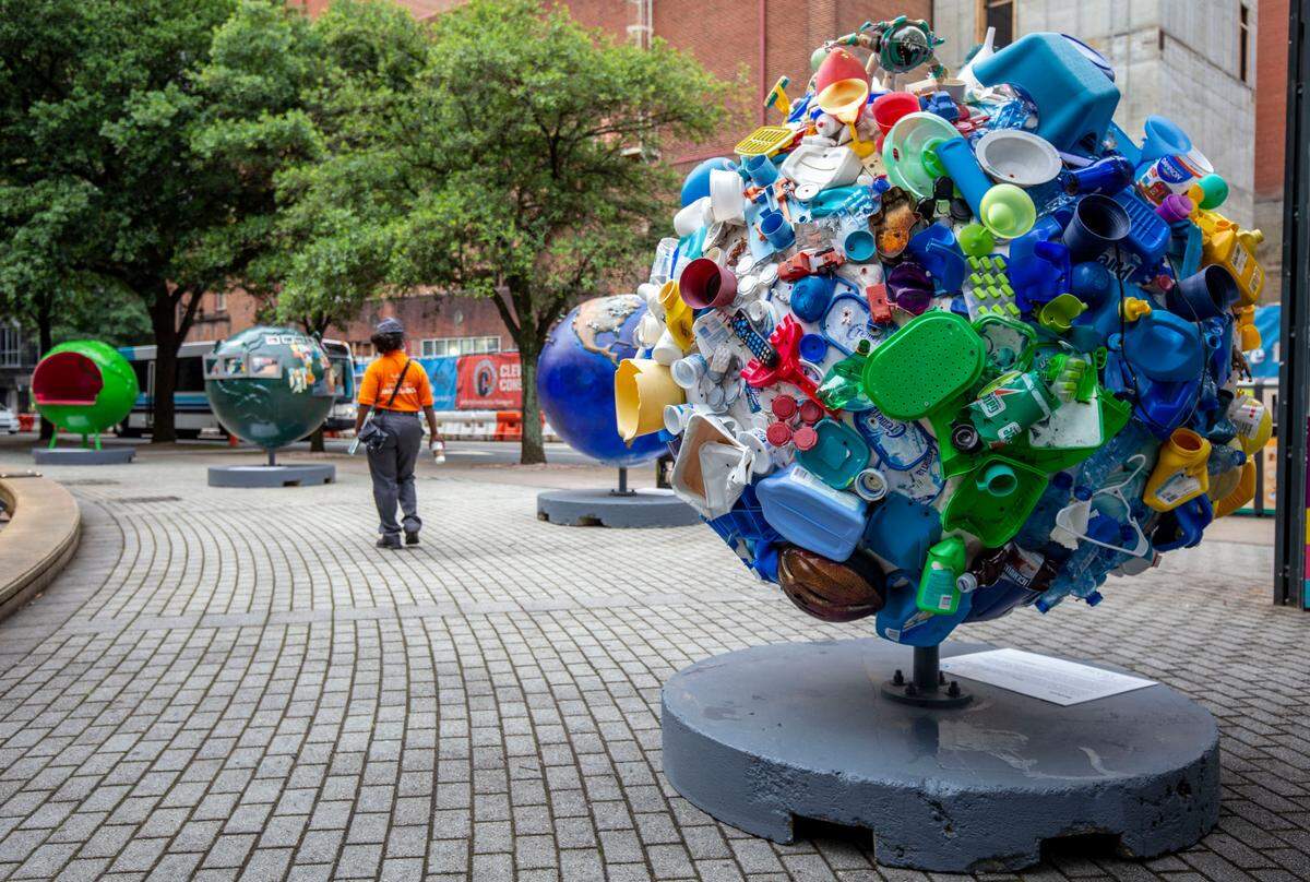 A passerby looks at the Cool Globes installation in front of the library in uptown Charlotte. Cool Globes is a traveling public art exhibition that features 35 globes, each with a message about global warming. Seven of the 5-foot diameter globes were made by Charlotte artists.