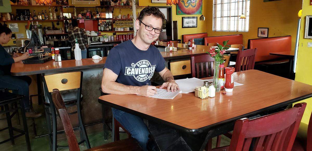 Scott Cavendish signs the lease at Zada Jane’s Corner Cafe in October.