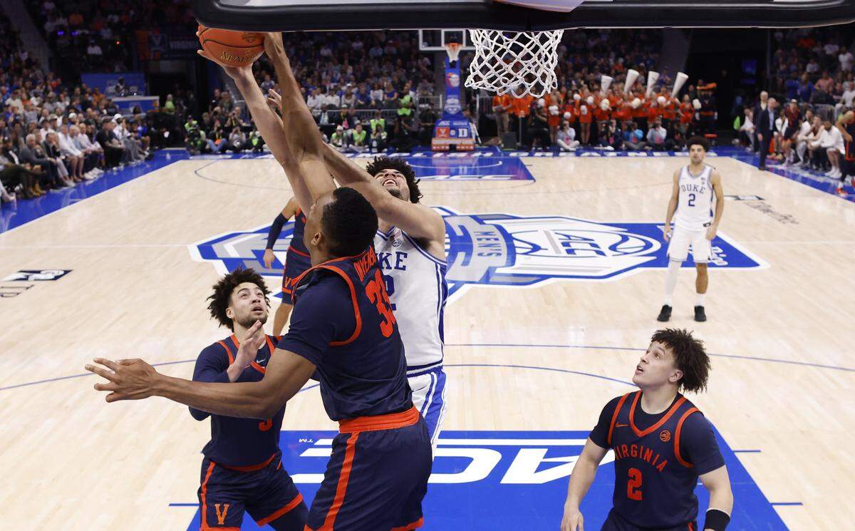 Virginia's Ugonna Onyenso (33) blocks a shot by Duke’s Cameron Boozer (12) during Duke’s 74-70 victory over Virginia in the finals of the 2026 ACC Men’s Basketball Tournament at the Spectrum Center in Charlotte Saturday.
