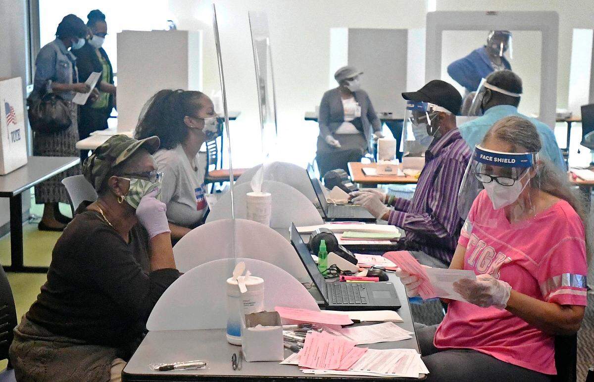 Poll workers process voters at the Beatties Ford Road Library early-voting site on Thursday, October 15, 2020.