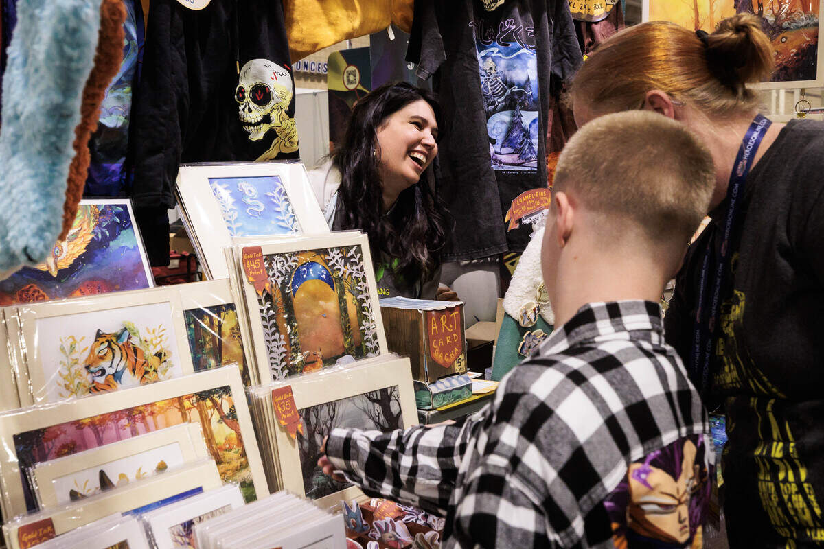 Licca Kirk, a Georgia-based illustrator converses with shoppers at her Heroes Convention booth on Friday, June 12, 2026 at the Charlotte Convention Center. Kirk’s work is primarily comprised of watercolor and hand-cut paper to make three-dimensional illustrations.