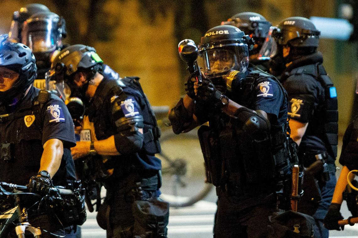 A police officer raises his paintball gun as he eyes the protesters walking by in uptown Charlotte, NC on Tuesday, June 2, 2020. Thousands gathered for a peaceful protest during the day until a group of nearly 300 continued to march through the streets of Charlotte.