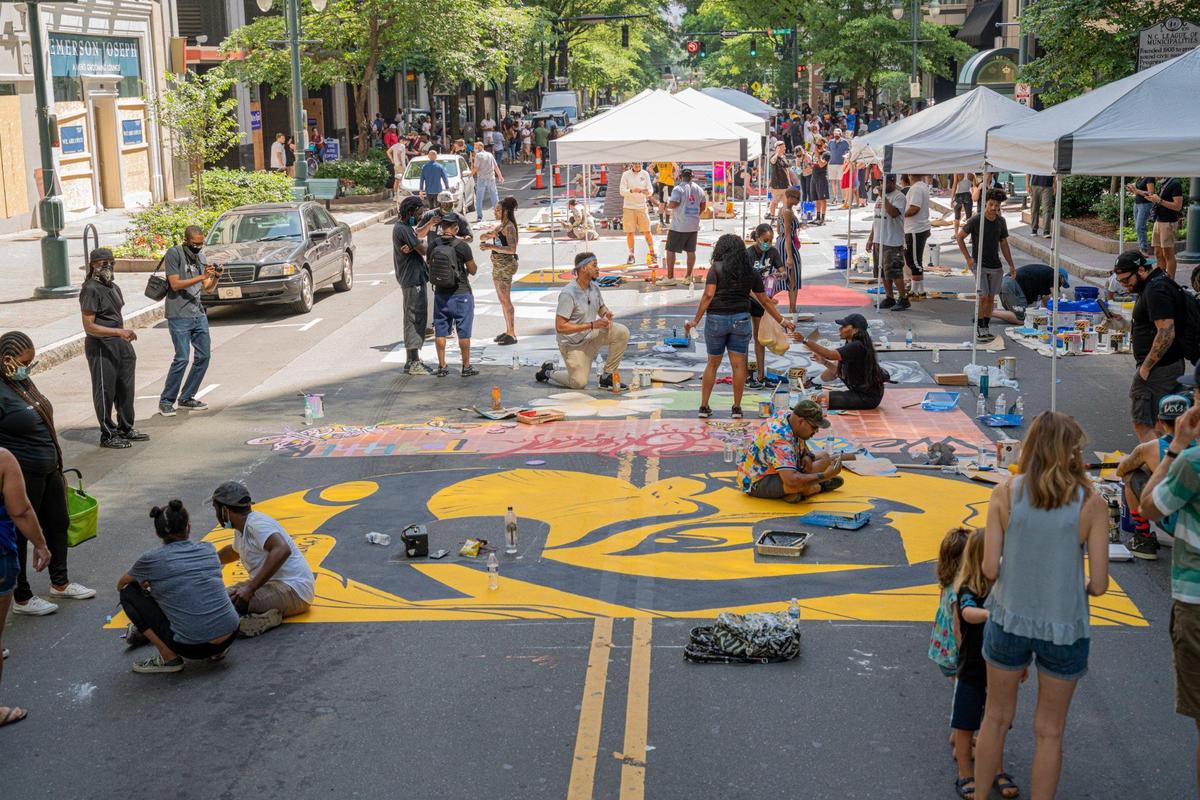 Charlotteans flood the streets to capture a glimpse of local artists contributing their individual letter designs to spell out Black Lives Matter on Tryon Street.