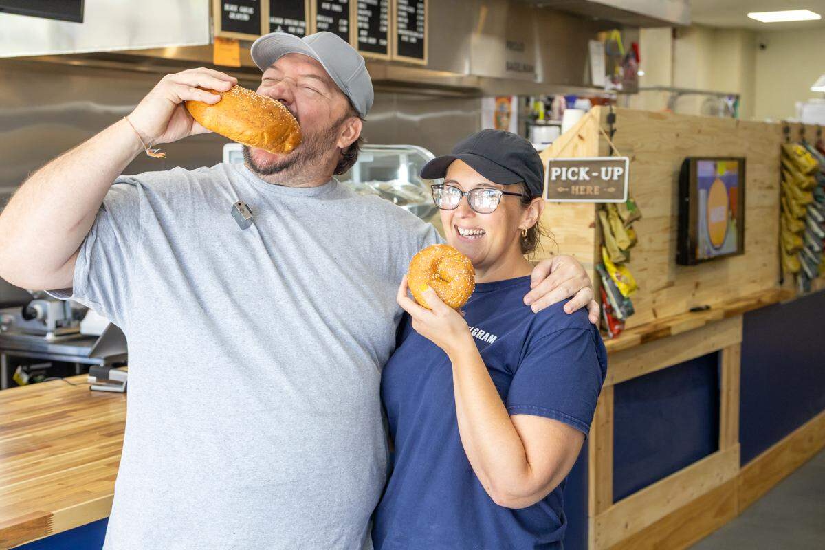 The owners of BagelGram taking holding bagels.