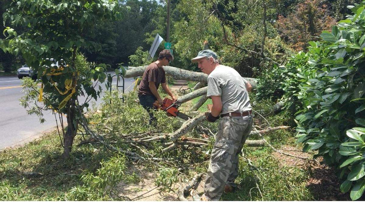 Residents Ben Lipscomb and Kent Johnson cleaned up debris from trees at the intersection of Providence Road and Queens Road West.