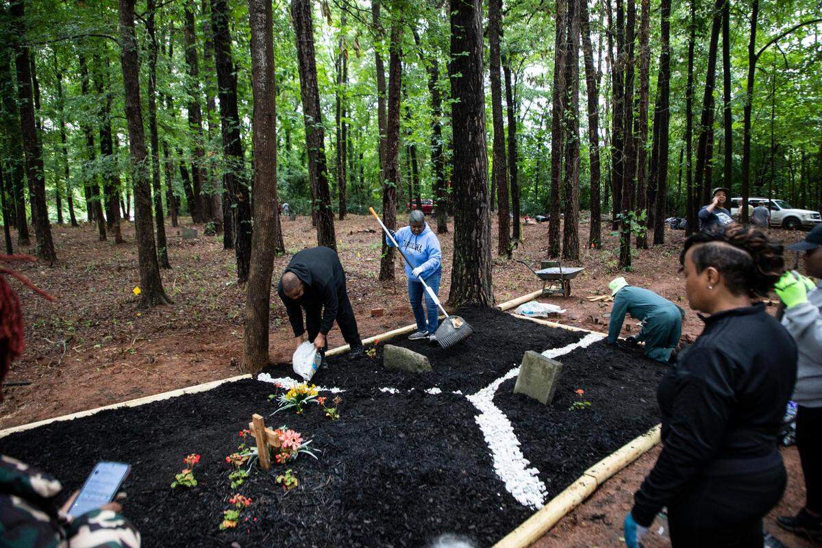 Family and friends of Deidra and Frank Wright work on the grave sites of Frank’s grandmother, sister, aunt and uncle at Cedar Grove Cemetery. Frank Wright only recently found out where his grandmother was buried.