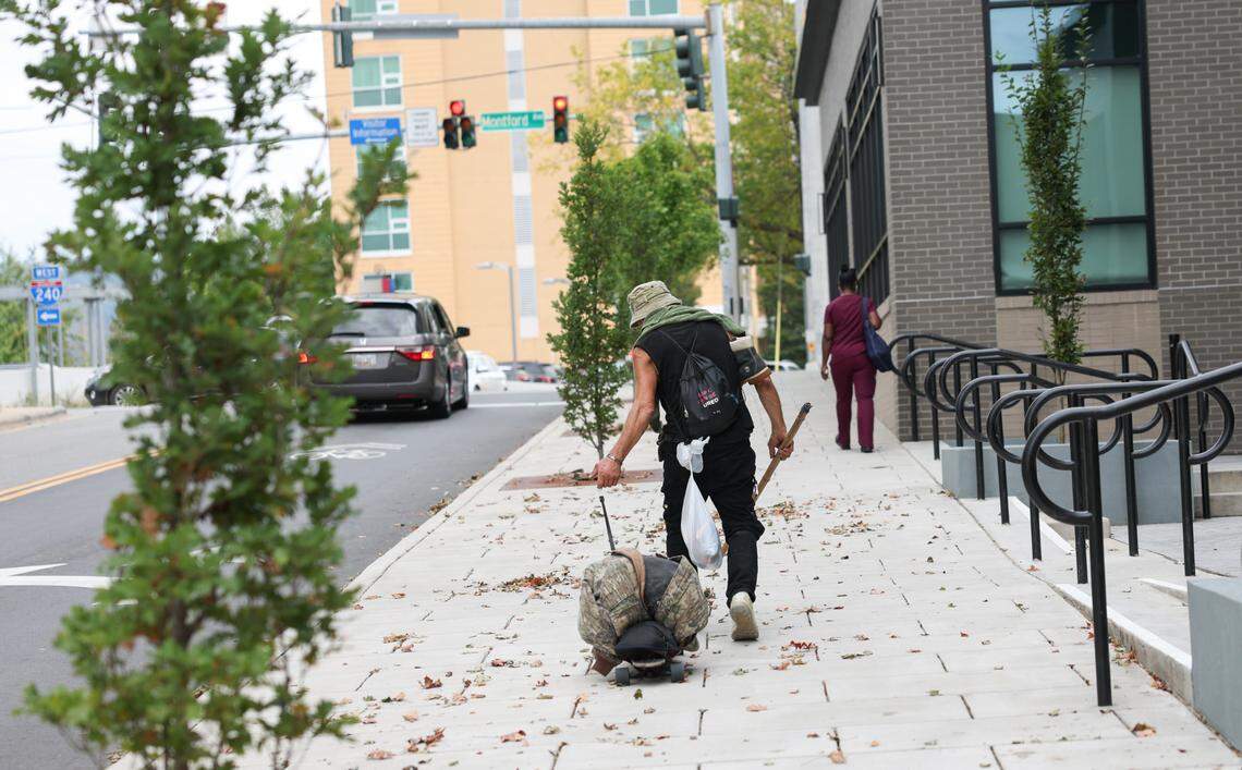 An unhoused man pulls his belongings piled on a skateboard up a sidewalk in downtown Asheville, NC on Friday, Oct. 4, 2024.