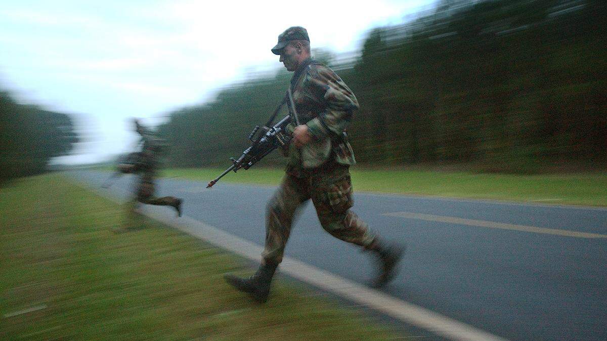 In this 2002 file photo, two U.S. Army Special Forces soldiers run across a road in rural Randolph County in the Uwharrie National Forest at dusk as they participate in the Robin Sage training exercise. The exercise for Special Forces applicants is the largest of its kind in the world involving over 7,000 square miles of central North Carolina. These men were part of a group observing “guerrilla” fighters tactics as they ambushed an opposing force vehicle. This summer’s exercise will occur in 19 counties Aug. 1-17.