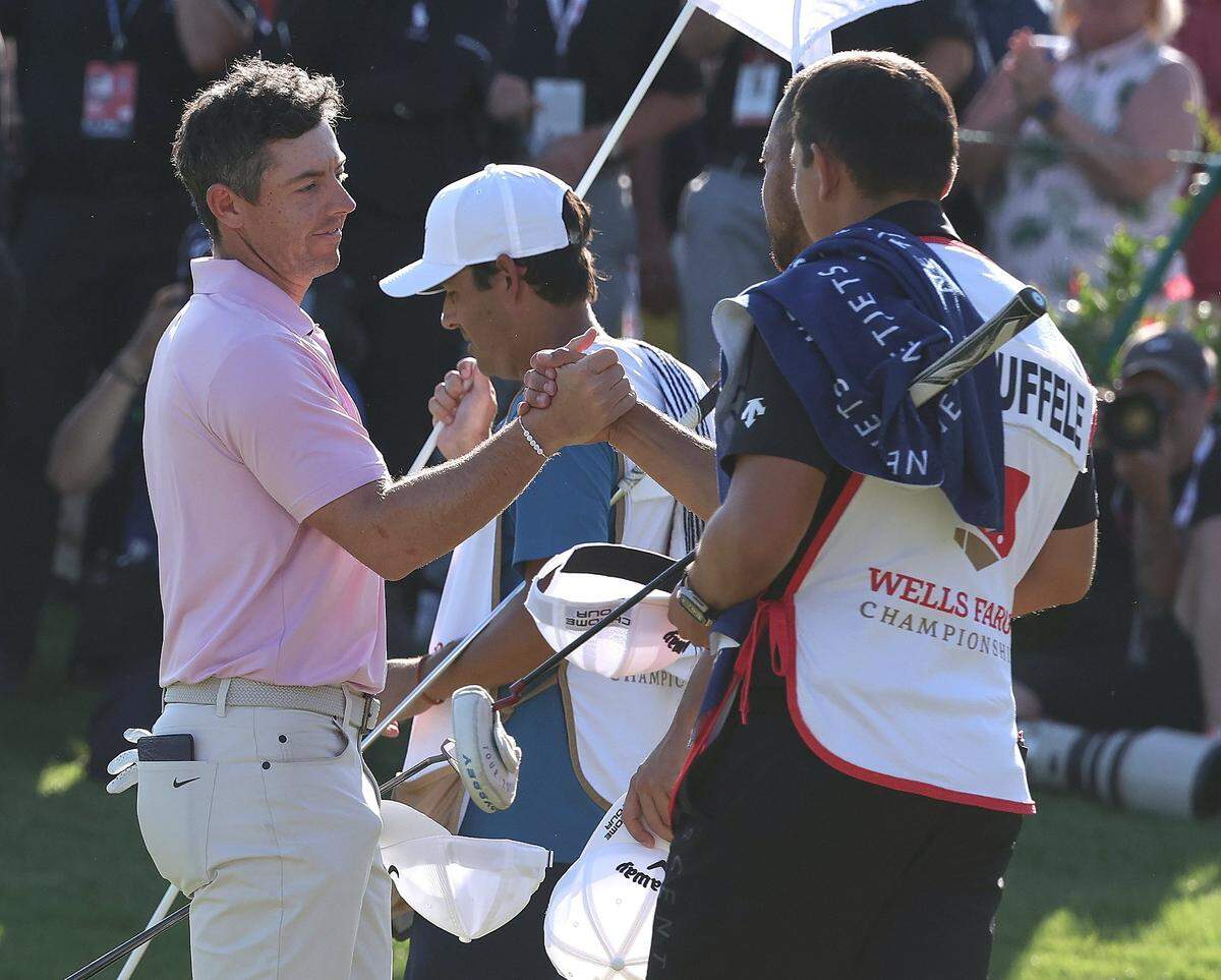 Rory McIlroy, left, shakes hands with Xander Schauffele, right, after McIlroy sank his final putt on the 18th green to win the Wells Fargo Championship at Quail Hollow Club in Charlotte, NC on Sunday, May 12, 2024. McIlroy won at -17.