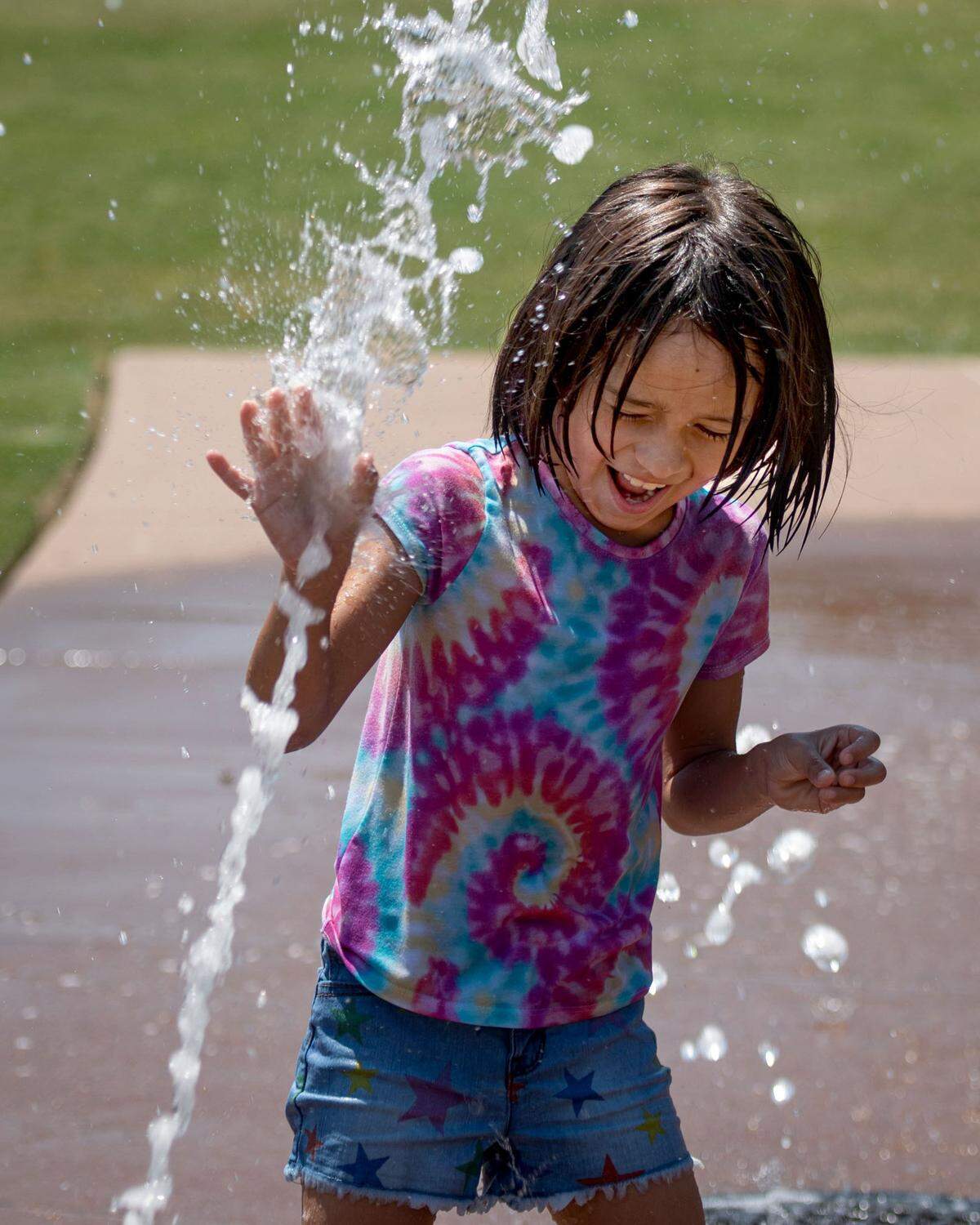 Jennica Perez, 7, plays at the sprayground at First Ward Park in uptown Charlotte, North Carolina, on Monday, June 13, 2022, as a heat wave passes through the city. Her parents, Victor and Erin Mendez, watch from the shade.