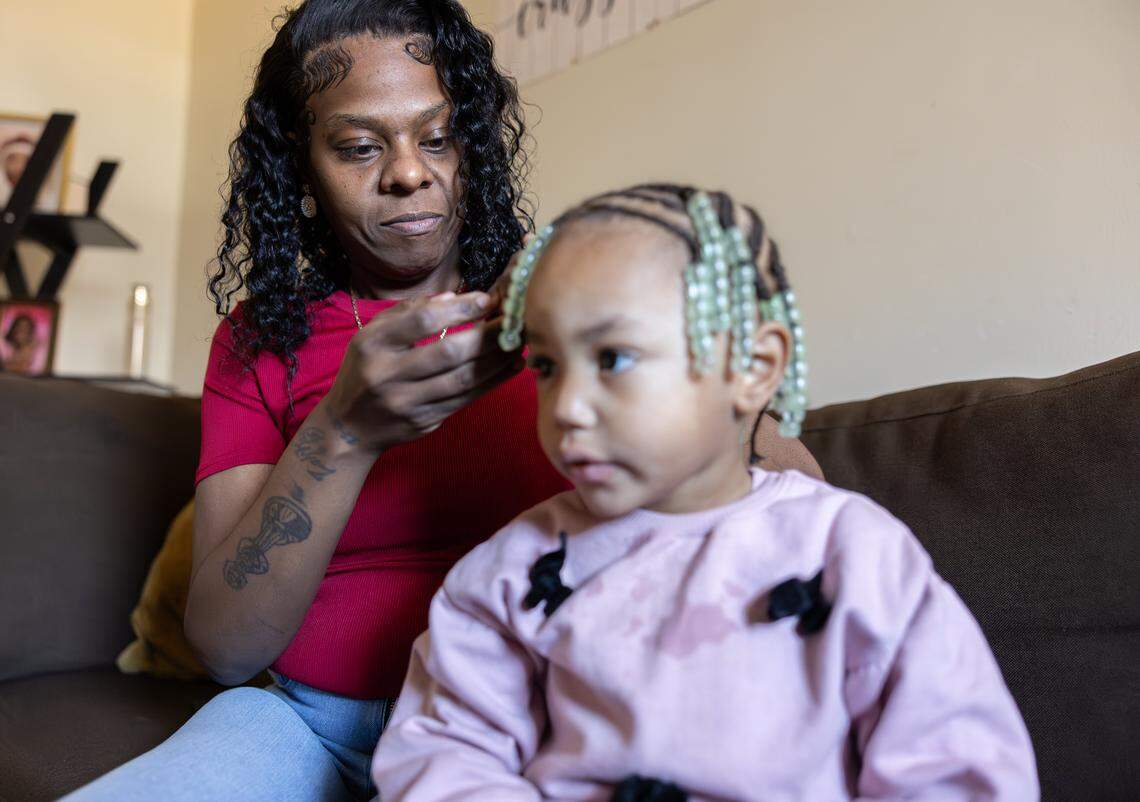 Tawanna Chambers, left, fixes Autumn Jackson's, 2, braids  at home in Albemarle, N.C., on Friday, January 16, 2025. Tawanna had weight loss surgery so she would be healthy enough to help take care of her grandchildren. After a long road of complications and more surgeries, she has only recently been able to care for them for short periods of time. 