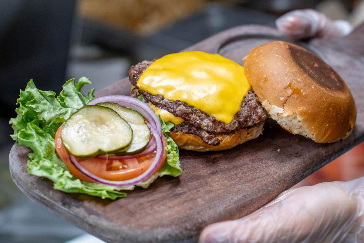 A burger at Bang Bang Burgers with two patties, American Cheese, onion, pickles, tomato, lettuce and a toasted bun.