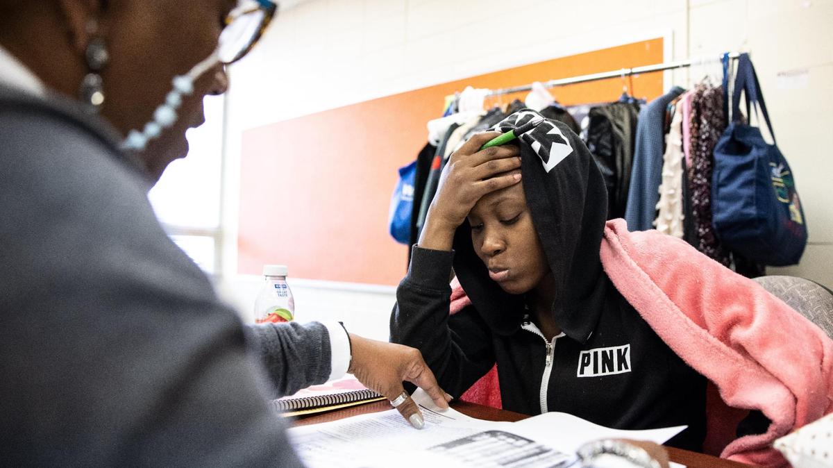 Camille Stephens, left, helps Mekayla Rodgers, 18, fill out a workbook during a session of the Juvenile Court Interventon Program in Charlotte, NC, on Tuesday, March 30, 2022. The Mecklenburg Council of Elders runs the program out of the former Plaza Road Academy in northeast Charlotte.