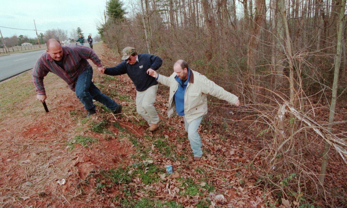 Volunteers Dale Costner, left, Donnie Martin and Sam Logan climb uphill along N.C. Highway 18 at the end of a search on Thursday, Feb. 17, 2000. After searchers found items thought to belong to 9-year-old Asha Degree, the search was concentrated on property on both sides of Highway 18 south of its intersection with N.C. Highway 180.