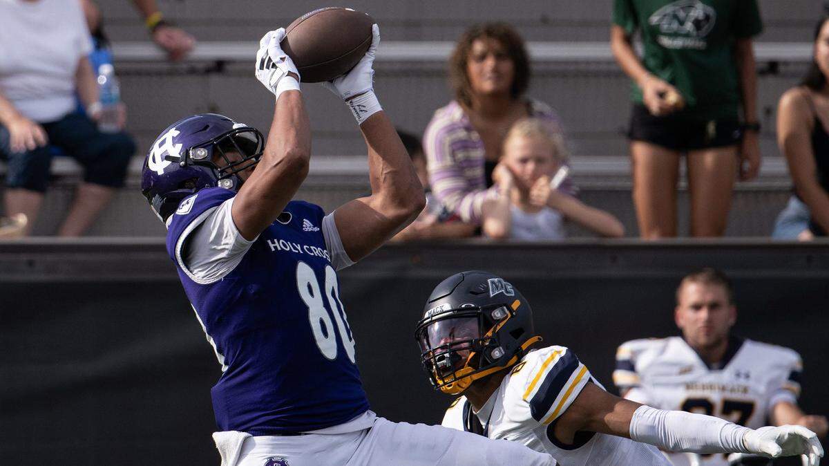 Holy Cross’s Jalen Coker hauls in a pass for a first down over Merrimack’s Darion McKenzie in 2023.