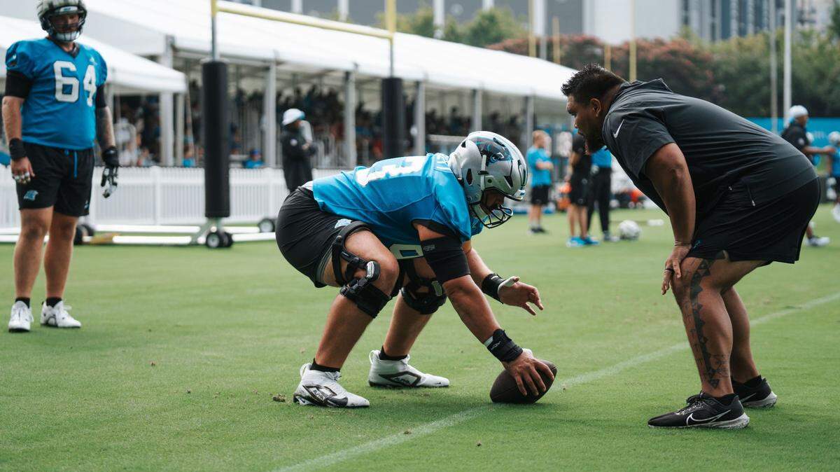 Carolina Panthers assistant offensive line coach Keli’i Kekuewa leads center Austin Corbett through a snapping drill during practice on the fields outside of Bank of America Stadium.