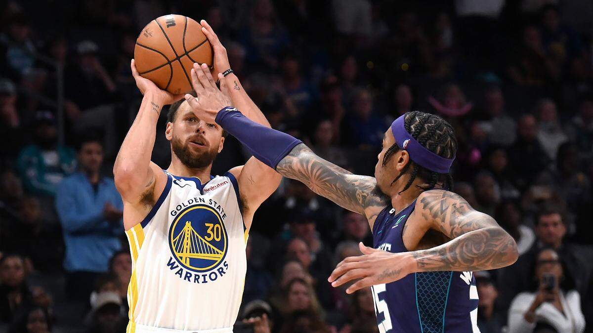 Charlotte Hornets forward PJ Washington, right, puts a hand in the face of Golden State Warriors guard Stephen Curry, left, on a shot attempt at Spectrum Center Saturday. Curry missed a buzzer-beater at the end of regulation, and the Hornets defeated the Warriors, 120-113, in overtime.