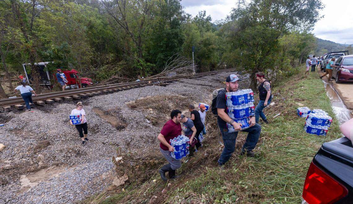 Western North Carolina residents salvage bottled water from a flooded tractor-trailer in Swannanoa on Sunday, Sept. 29, 2024. The remnants of Hurricane Helene caused widespread flooding, downed trees, and power outages in western North Carolina.