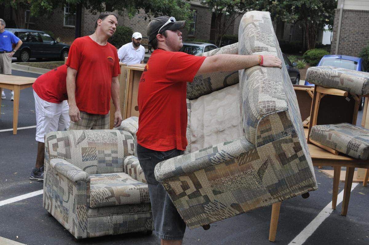 08.05.2011: Classic City Liquidators movers, Connors Saunders(R) carry a chair to the trailer while Michael Bostic wait in line. __University Walk Apartments in partnership with Classic City Liquidators out of Athens,Georgia, donated over 3,840 pieces of furniture to Habitat for Humanity Restore. After all is completed, sixteen 53 ft tractor trailer trucks will be used to store and distribute all the furniture to other Habitat Restores from Greensboro, N.C. to Columbia, S.C.__T.Ortega Gaines - ogaines@charlotteobserver.com