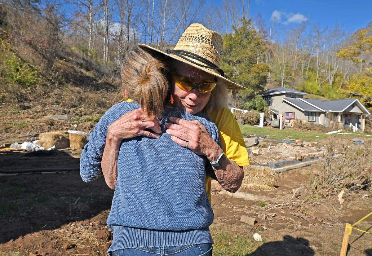 Sharon Hughes of Burnsville, N.C., right, is hugged by Chris Shelnut, back to camera, on Nov. 25. Hughes had to flee her over 100-year-old home as the heavy rain from Hurricane Helene caused the Cane River to overflow its banks.
