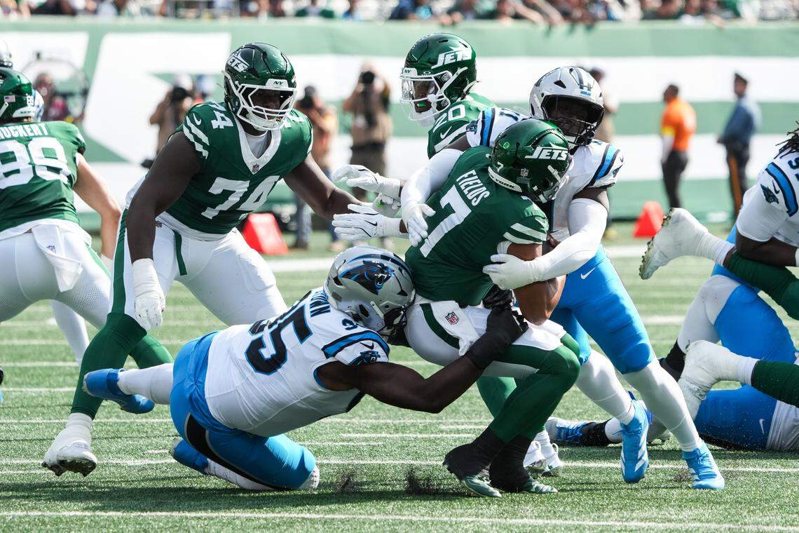 New York Jets quarterback Justin Fields (7) is brought down by Carolina Panthers defensive end Derrick Brown (95) and outside linebacker Nic Scourton (11) at MetLife Stadium Oct. 19, 2025