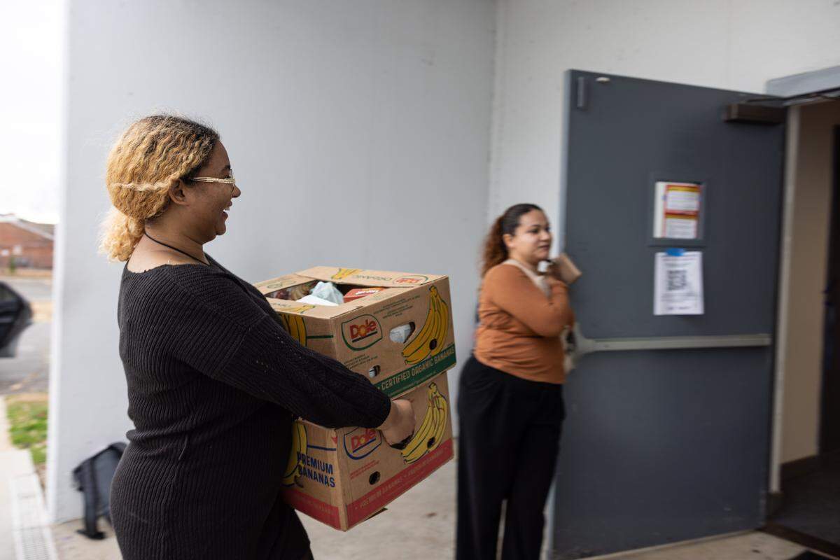 Kayla Neal, left, brings inside a box of food donations as Anna Hernandez holds the door at Tabernaculo de Garcia in Charlotte, N.C., on Tuesday, November 25, 2025. Volunteers delivered more than 300 boxes in one week to families in need.