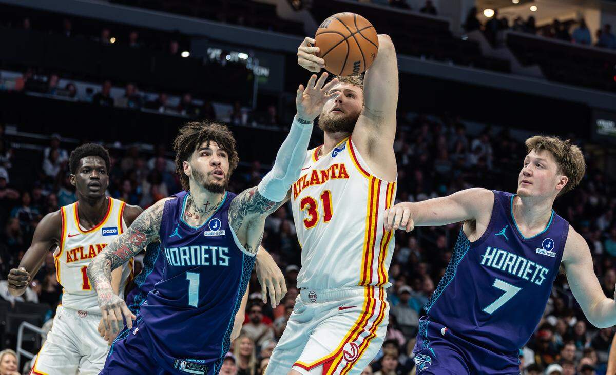 Charlotte Hornets guard LaMelo Ball, left, reaches for the rebound past Atlanta Hawks center Jock Landale at the Spectrum Center in Charlotte, N.C., on Wednesday, February 11, 2026.
