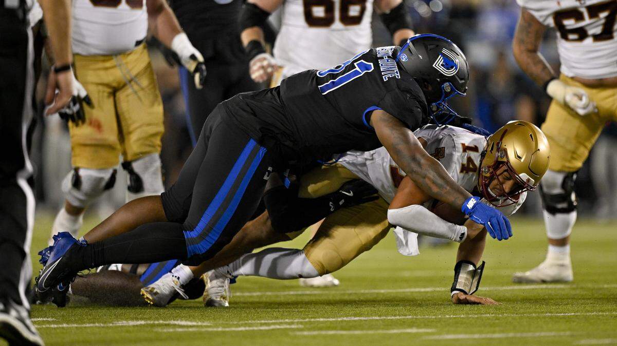 Nov 16, 2024; Dallas, Texas, USA; Boston College Eagles quarterback Grayson James (14) is sacked by SMU Mustangs linebacker Kobe Wilson (24) and defensive lineman Jared Harrison-Hunte (81) during the second half at Gerald J. Ford Stadium. Mandatory Credit: Jerome Miron-Imagn Images